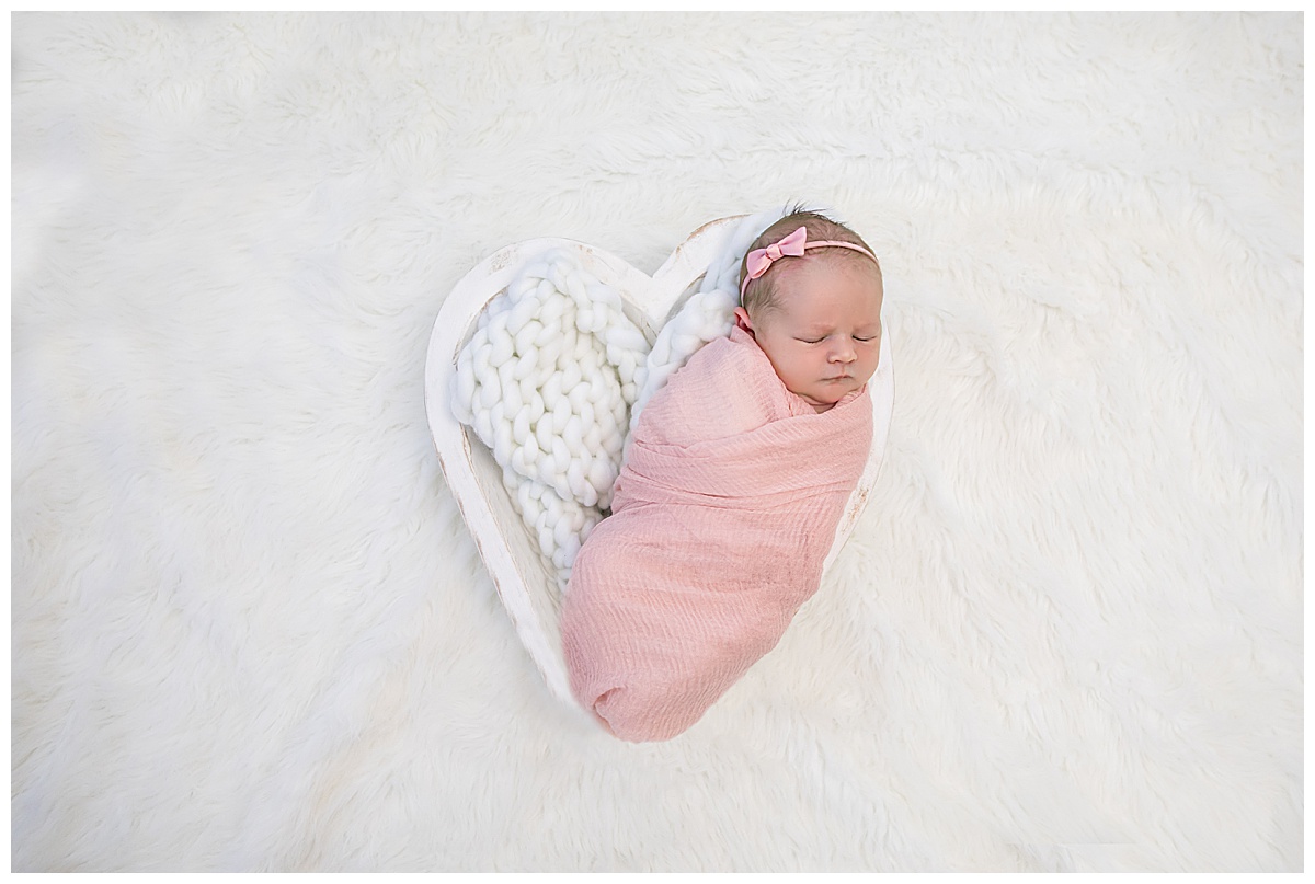 baby girl in newborn pink wrap and heart shaped bowl
