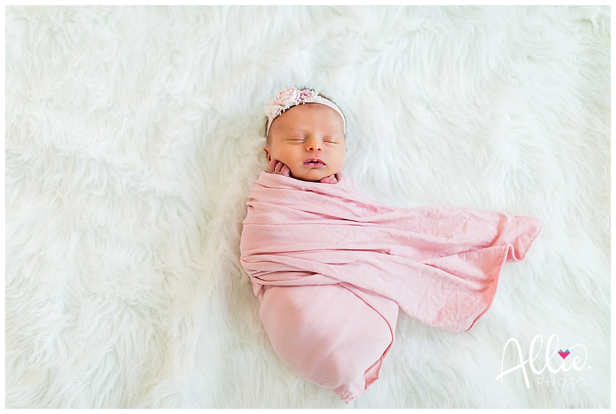 baby girl in pink wrap with headband at home newborn photos