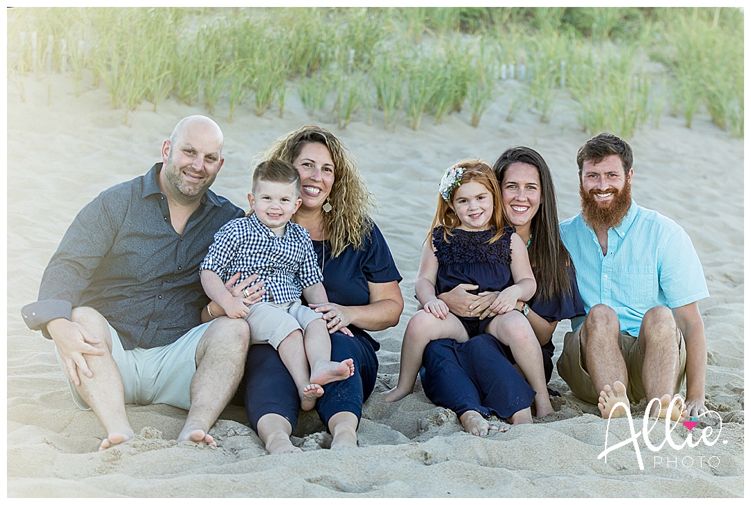 group of family and kids sitting on the beach for portraits